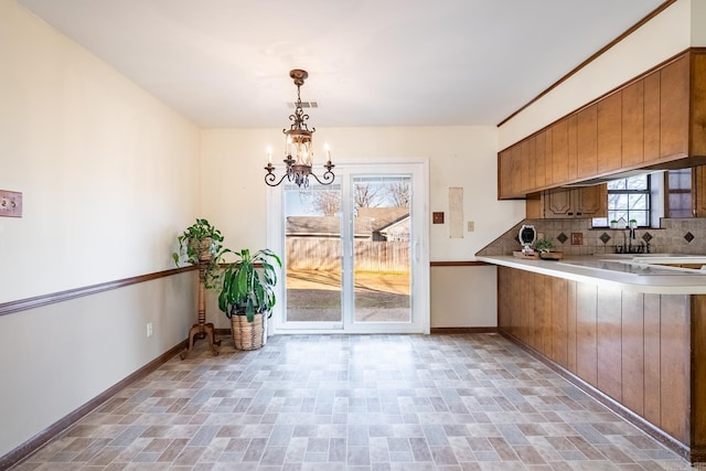 kitchen featuring tasteful backsplash, a notable chandelier, decorative light fixtures, and sink