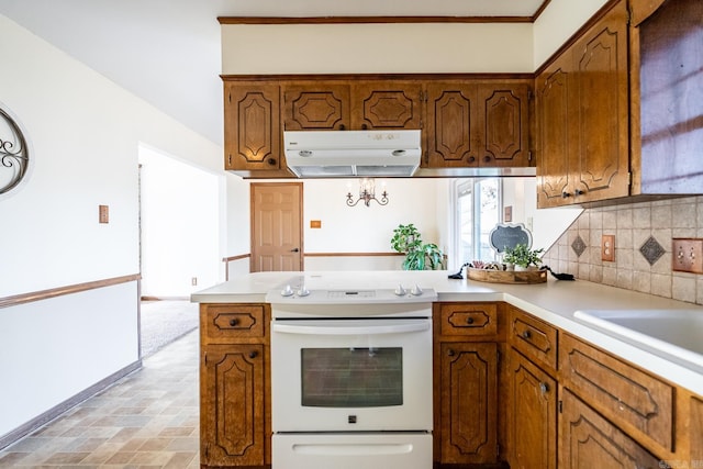 kitchen featuring kitchen peninsula, sink, decorative backsplash, and white range with electric stovetop