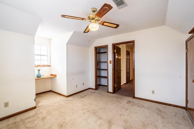 interior space with vaulted ceiling, light carpet, and a textured ceiling