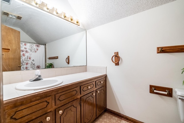 bathroom featuring vanity, vaulted ceiling, and a textured ceiling