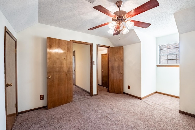 unfurnished bedroom with vaulted ceiling, light colored carpet, ceiling fan, and a textured ceiling