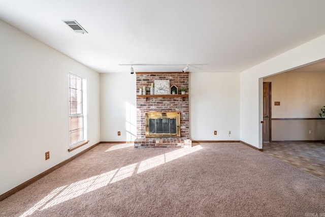 unfurnished living room with track lighting, carpet floors, and a brick fireplace