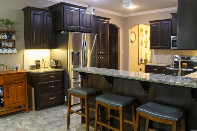 kitchen with a breakfast bar, appliances with stainless steel finishes, dark brown cabinets, tasteful backsplash, and light stone countertops