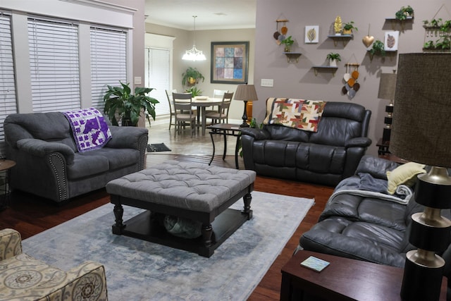 living room with dark wood-type flooring, ornamental molding, and a notable chandelier