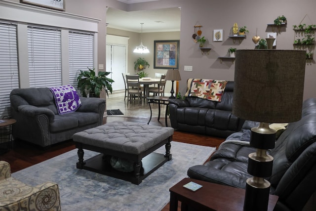 living room with hardwood / wood-style flooring, ornamental molding, and a chandelier