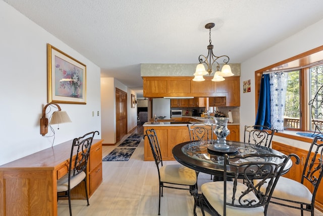 dining area featuring sink, a textured ceiling, and a chandelier