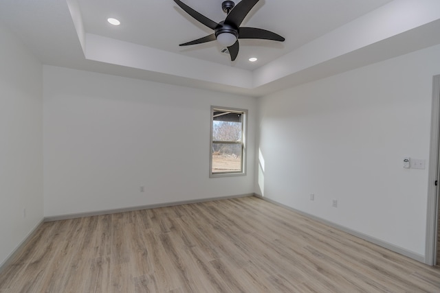 spare room featuring light hardwood / wood-style floors, a raised ceiling, and ceiling fan