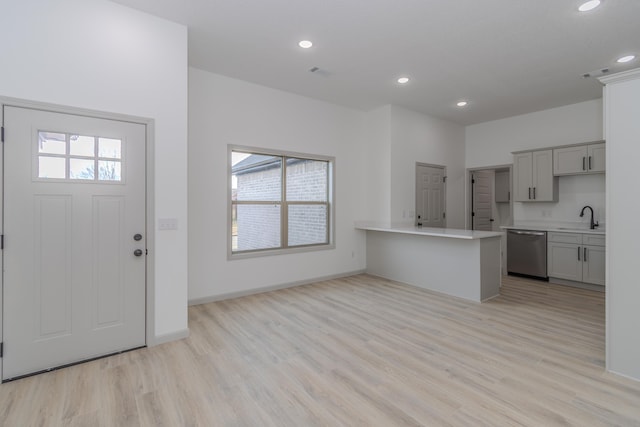 kitchen with dishwasher, sink, kitchen peninsula, and light wood-type flooring