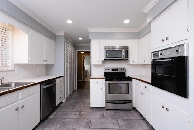 kitchen featuring white cabinetry, appliances with stainless steel finishes, crown molding, and backsplash