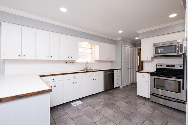 kitchen featuring sink, ornamental molding, white cabinets, and appliances with stainless steel finishes