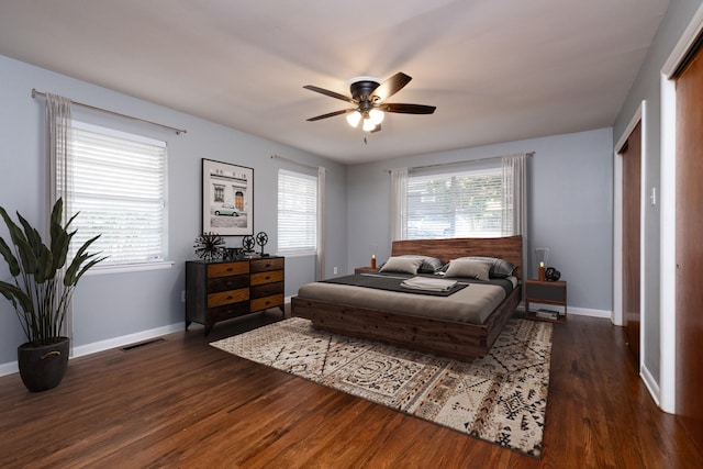 bedroom with multiple windows, ceiling fan, and dark hardwood / wood-style flooring