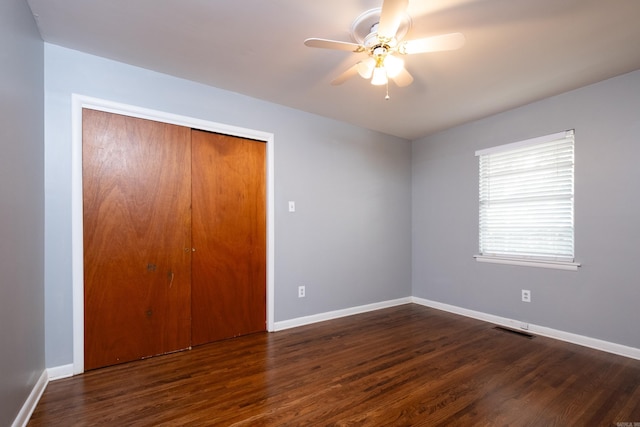 unfurnished bedroom featuring dark wood-type flooring, ceiling fan, and a closet