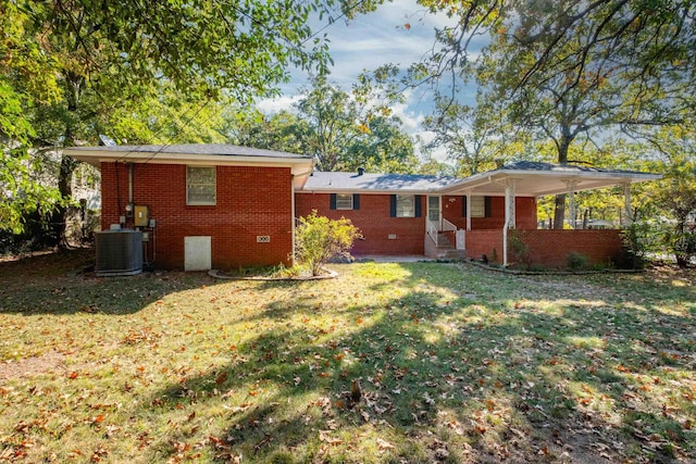 back of property with central AC and a lawn