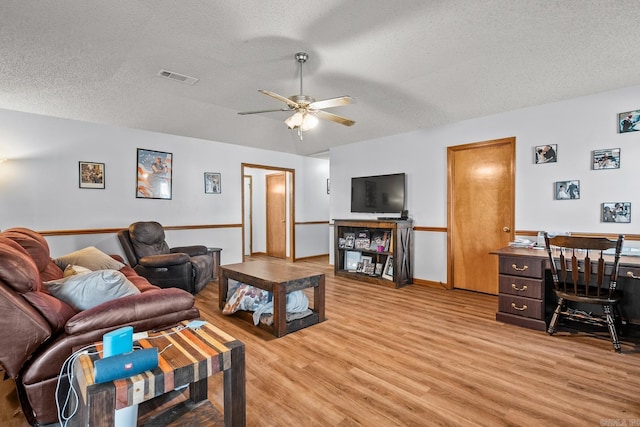 living room with ceiling fan, light hardwood / wood-style flooring, and a textured ceiling