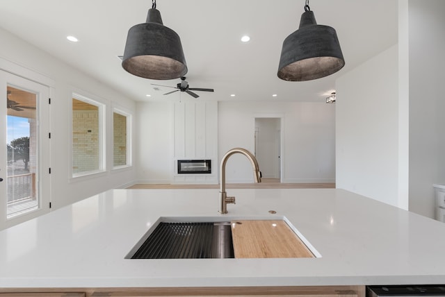 kitchen featuring hanging light fixtures, a fireplace, and sink