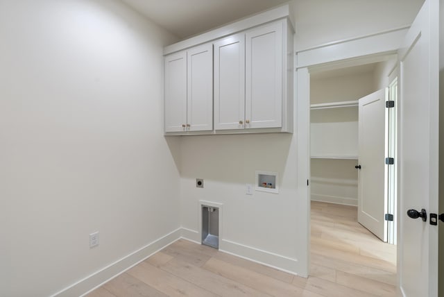 clothes washing area featuring washer hookup, cabinets, light hardwood / wood-style flooring, and hookup for an electric dryer