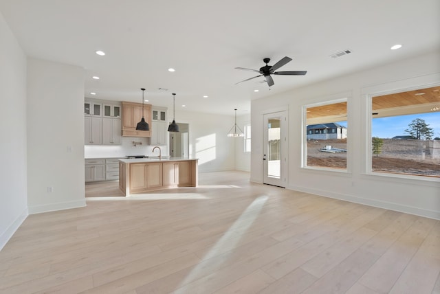 unfurnished living room featuring sink, ceiling fan with notable chandelier, and light hardwood / wood-style flooring