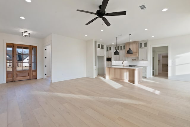 unfurnished living room featuring ceiling fan, sink, and light hardwood / wood-style floors