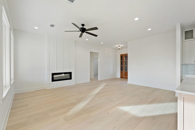 unfurnished living room featuring ceiling fan, a fireplace, and light hardwood / wood-style flooring