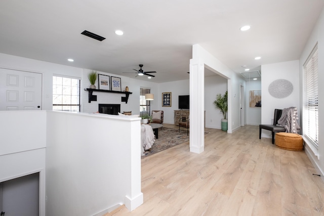 living room featuring light hardwood / wood-style floors, a large fireplace, and ceiling fan