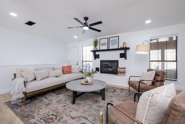 living room featuring a brick fireplace, ceiling fan, and light hardwood / wood-style flooring