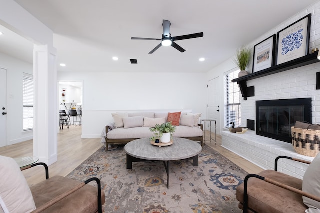 living room with ceiling fan, a fireplace, and light hardwood / wood-style floors