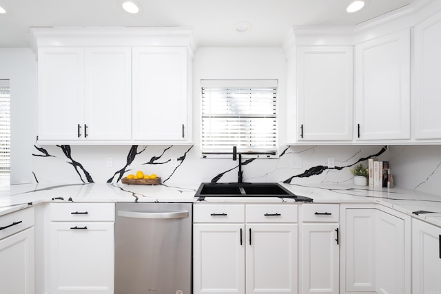 kitchen featuring sink, backsplash, light stone countertops, and white cabinets