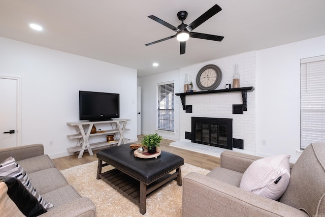 living room with ceiling fan, a fireplace, and light hardwood / wood-style floors