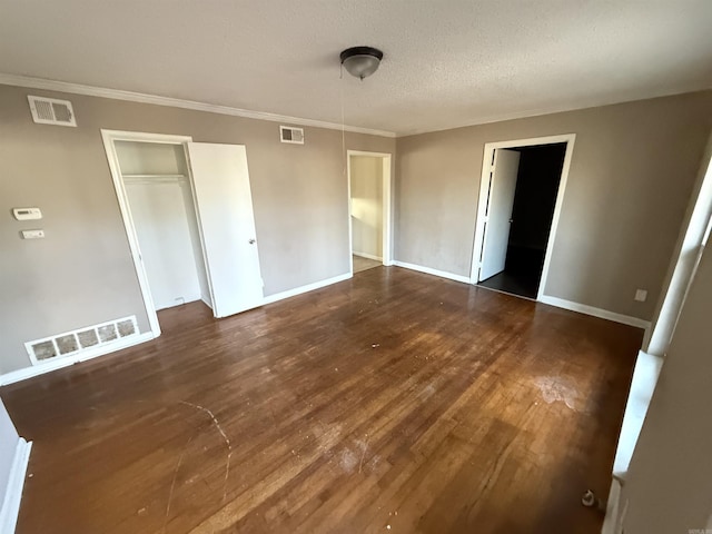 unfurnished bedroom featuring crown molding, dark wood-type flooring, a textured ceiling, and a closet