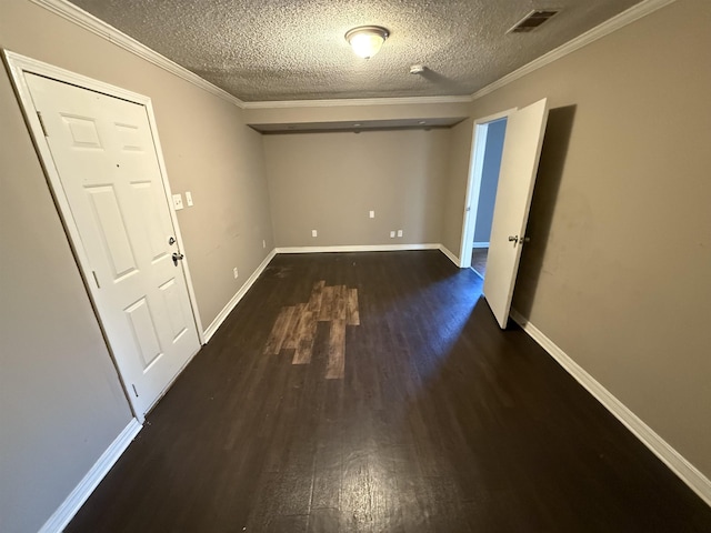 spare room featuring dark wood-type flooring, ornamental molding, and a textured ceiling