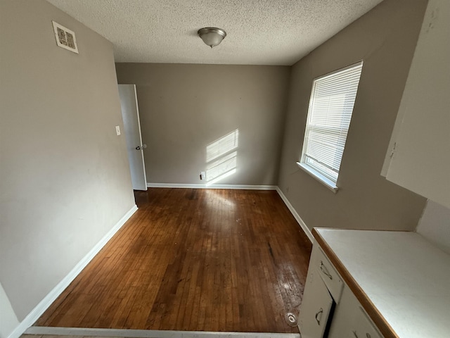 unfurnished dining area featuring dark hardwood / wood-style floors and a textured ceiling