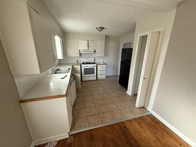 kitchen featuring sink, white gas stove, white cabinetry, a textured ceiling, and black refrigerator