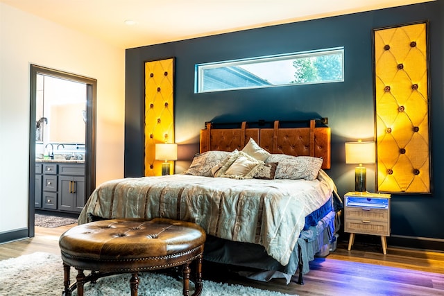 bedroom featuring ensuite bath and light hardwood / wood-style flooring