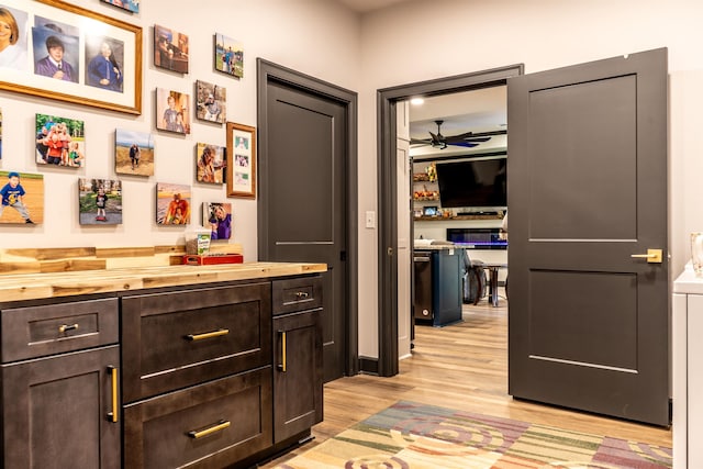 interior space with ceiling fan, dark brown cabinets, wooden counters, and light hardwood / wood-style floors