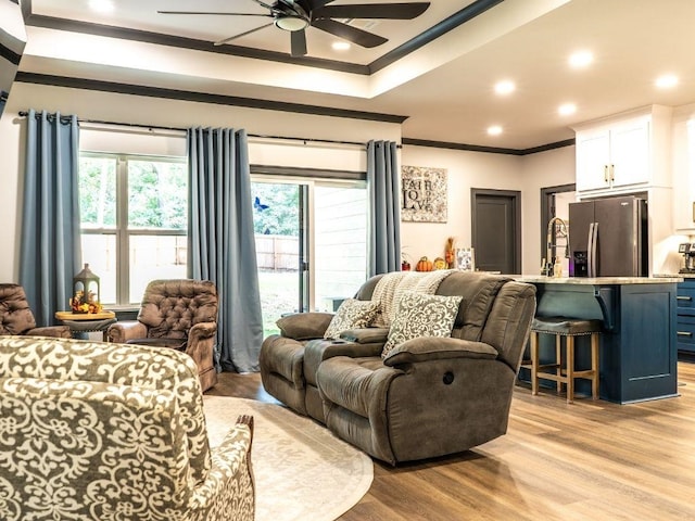 living room with crown molding, light hardwood / wood-style flooring, and ceiling fan