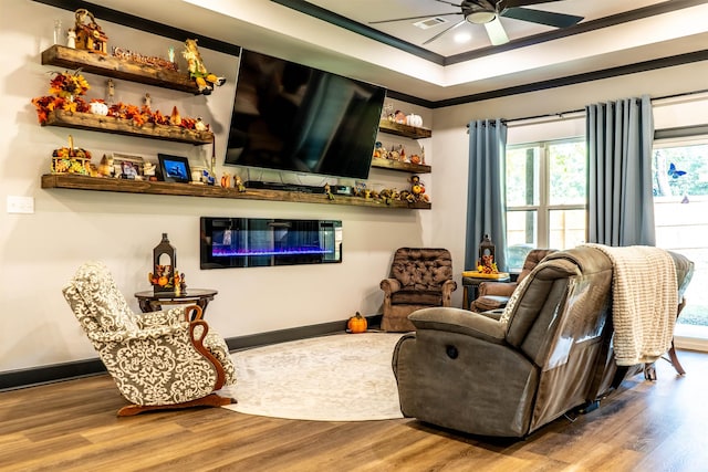 living room with a raised ceiling, hardwood / wood-style floors, and ceiling fan