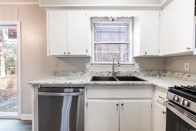 kitchen with stainless steel appliances, white cabinetry, sink, and light stone counters