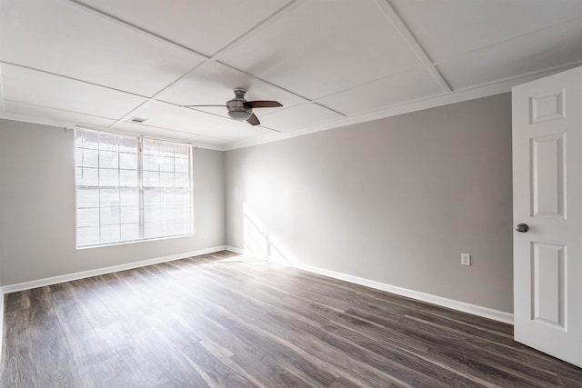 spare room with ornamental molding, dark wood-type flooring, a drop ceiling, and ceiling fan