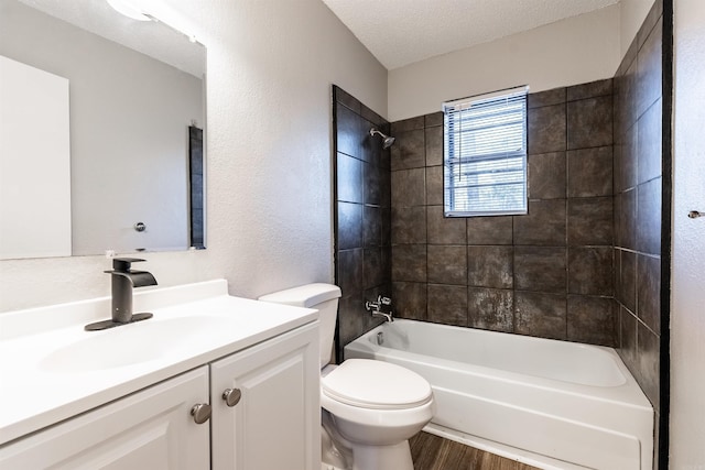 full bathroom featuring hardwood / wood-style flooring, tiled shower / bath combo, vanity, a textured ceiling, and toilet