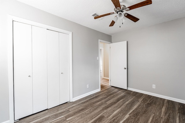 unfurnished bedroom with ceiling fan, dark wood-type flooring, a textured ceiling, and a closet