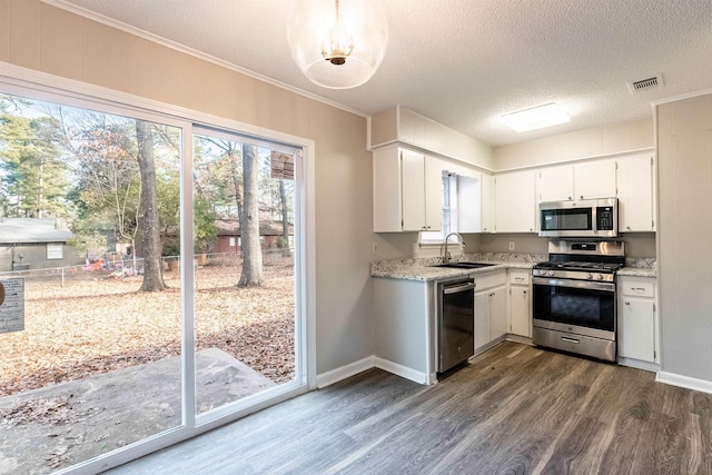 kitchen with sink, appliances with stainless steel finishes, white cabinetry, light stone countertops, and dark hardwood / wood-style flooring