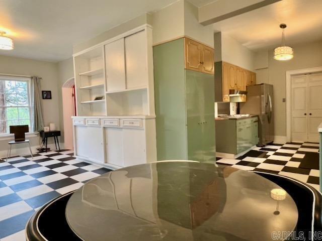 kitchen with beamed ceiling, light brown cabinets, stainless steel fridge, and decorative light fixtures