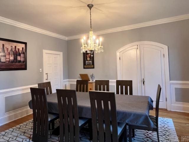 dining area with crown molding, hardwood / wood-style floors, and a notable chandelier