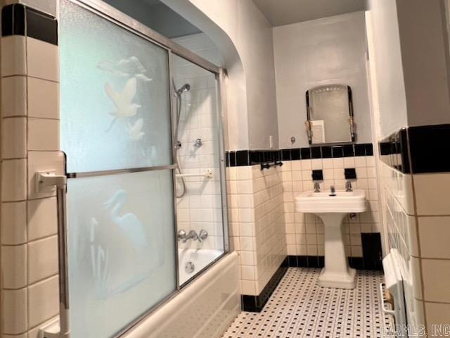 bathroom with tile walls, tile patterned flooring, and shower / bath combination with glass door