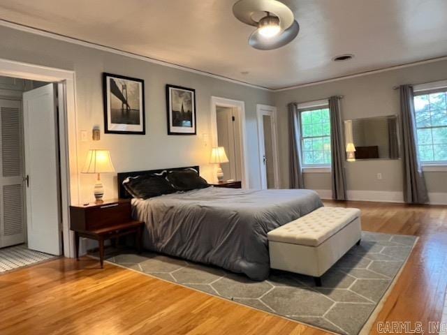 bedroom featuring multiple windows, crown molding, and hardwood / wood-style floors