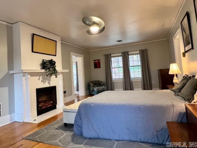 bedroom with ornamental molding and hardwood / wood-style floors