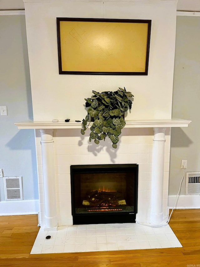 interior details with a tiled fireplace and hardwood / wood-style floors