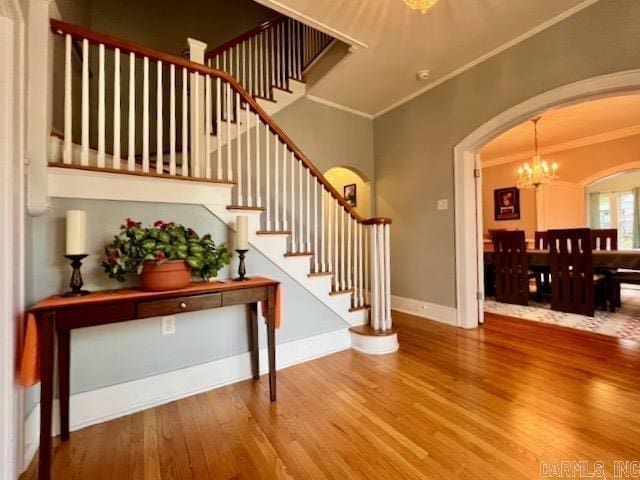 entrance foyer with hardwood / wood-style floors, ornamental molding, and a chandelier