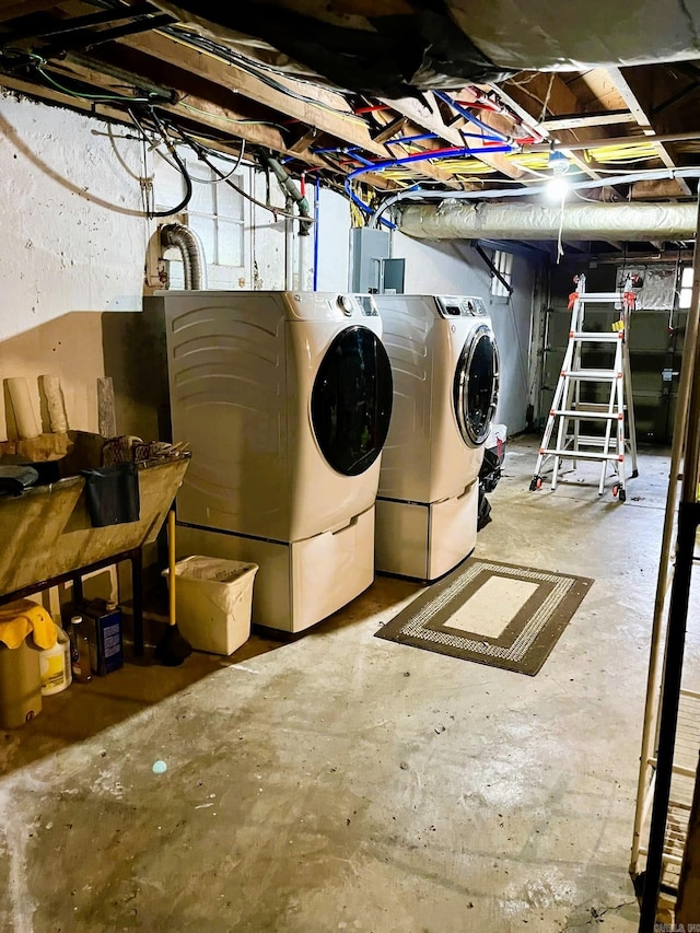 basement with electric panel and washing machine and clothes dryer