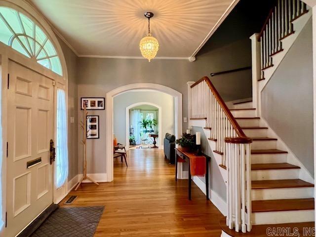 entryway with crown molding, hardwood / wood-style flooring, and an inviting chandelier